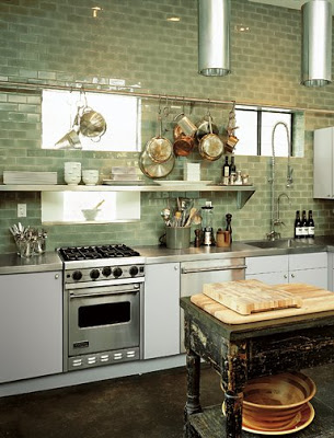 Small kitchen with open stainless steel shelf, Ann Sacks Capriccio ceramic field tiles in green backsplash, stainless counter tops and a worn looking black country table doubles as a center island