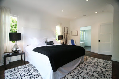 Master bedroom with white upholstered head board, silver lamps and a Moroccan wool rug