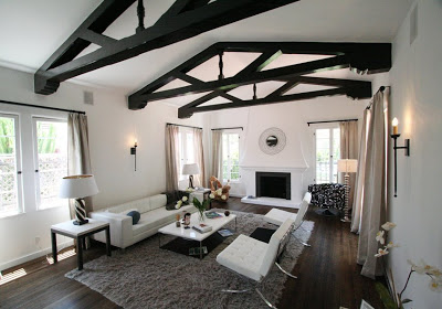 Living room with dark hardwood floor, white walls and vaulted ceiling with dark wood beams, and a neutral color palette