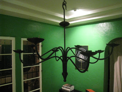 Black candelabra hanging from the ceiling in a Kelly Green dining room