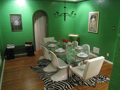 Kelly Green dining room with a zebra print rug surrounded by four Panton chairs and two leather and chrome host chairs at each end of the table