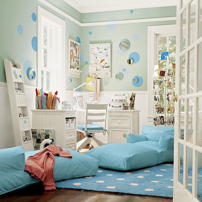 Kid's bedroom with white desk and hair, mint green walls with blue dots and round mirrors, blue rug with white polka dots and two light blue floor seats