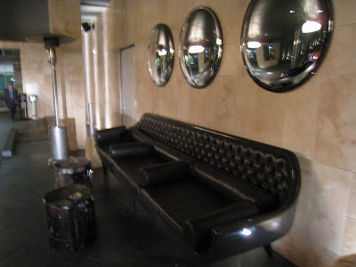 Valet area of The Thompson Hotel with three round convex mirrors over a leather sofa