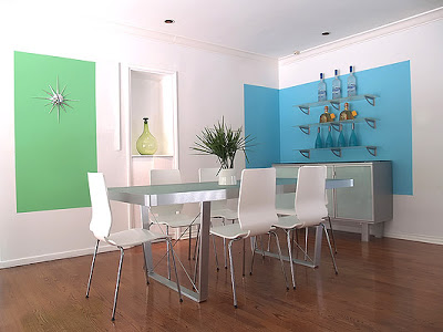 Bright modern dining room designed by Vanessa de Vargas with blue and green blocks of color on white walls, sleek white dining room chairs and a frosted glass and metal dining table and buffet