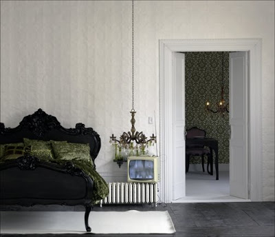 Bedroom with a black carved wood headboard and frame, white walls, black wood floor and a black chandelier with green crystals
