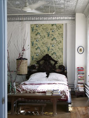 Bedroom with a pressed tin ceiling, floral wall paper, texture walls, a dark wood bench at the foot of the bed and a black carved headboard