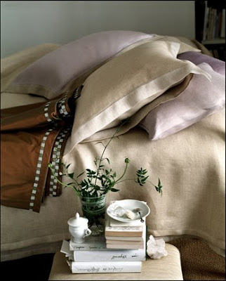 Bedroom with tan and pale purple bedding and a small nightstand 