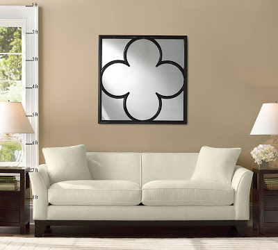 Black finish wood frame quatrefoil wall mirror from Pottery Barn in a living room with a white sofa and two wood end tables