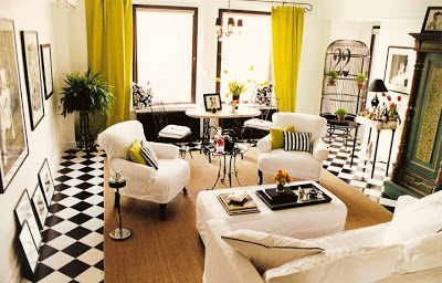 Living room by Jeff Andrews Design with black and white checker board tile floor, white walls, grand black paned windows with chartreuse curtains and white slipcovered armchairs and sofa