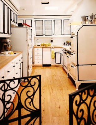 Kitchen by Jeff Andrews Design with white cabinets with black borders and trim, white drawers with black pulls and wood block countertops and floor