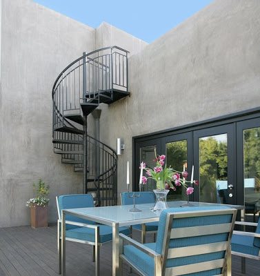 Back of house after The Sunset Team's La Kaza Design's redo with iron spiral staircase and a dining area