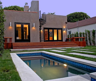 Backyard after The Sunset Team's La Kaza Design's redo with dark wood stained French doors and a small pool with mosaic blue tiles
