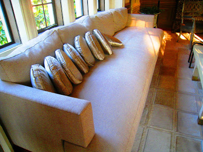 Long white sofa with round satin pillows under the window in the master bedroom in the Greystone Mansion