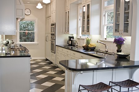 Kitchen after remodeling by Newman & Wolen Design with glass cabinets, black quartz counter tops, stainless appliances and a grey and white plaid floor