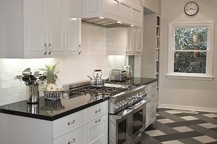 Kitchen after remodeling by Newman & Wolen Design with black quartz counter top, grey cabinets with molding detail, off white subway tile backsplash and a stainless gourmet range and oven