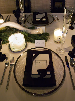 Silver rimmed glass plates frame black napkins and a Jo Malone party favor