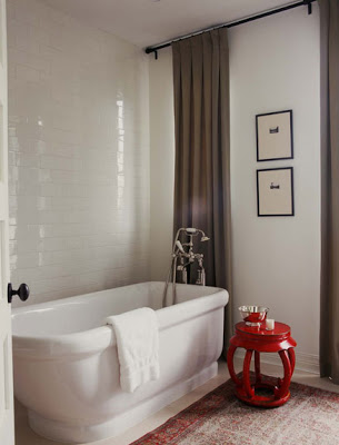Master bathroom with floor to ceiling white subway tile wall, stand alone tub and a red lacquer stool