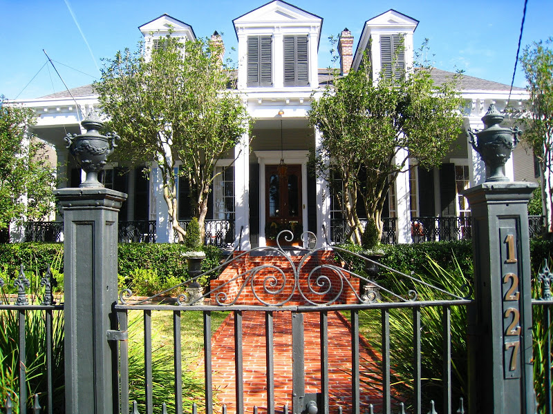 Iron gate outside a classic home with a red brick walkway and white columns