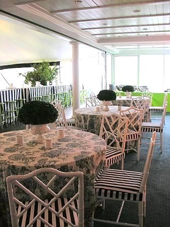 Dining tables at a wedding designed by Delaney Todd Bagwell with black and white tolie tablecloths, white Chippendale chairs with black and white striped seat cushions and green centerpieces