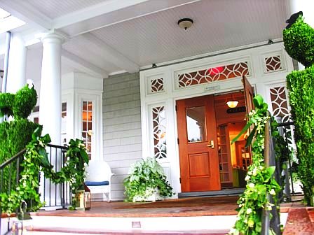 Exterior of a club prepared for a wedding with green garlands on the stair railing and poultry inspired topiaries by Delaney Todd Bagwell