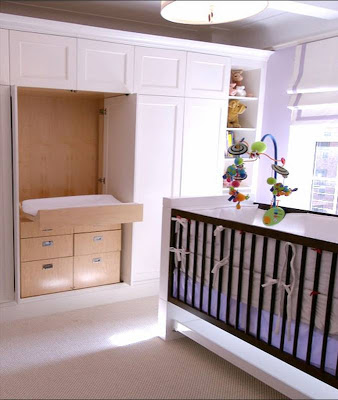 Doors in a built in closet in a New York nursery open to reveal a changing table by Area Interior Design