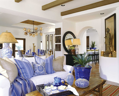 White open plan living room by Barclay Butera with blue accents in the form of pillows, vases and pottery 