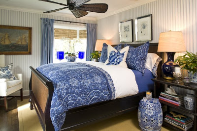 Blue guest bedroom by Barclay Butera with striped wallpaper, blue jaquard bedding, blue and white Chinese garden stool and a mahogany sleigh bed