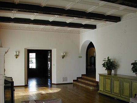 Living room before remodeling with hardwood floor, arched door, and a beamed and paneled ceiling
