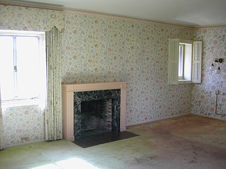 Master bedroom with floral wallpaper, old carpet and a fireplace before remodeling