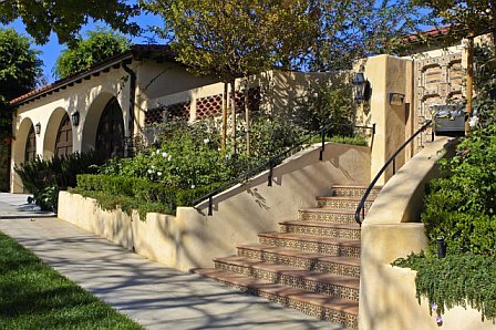 Exterior of a Cheviot Hills home after remodeling with stacked Spanish roof tile frill, arched garage doors and a carved wood gate entry door