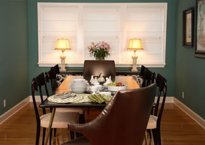 Dark teal dining room with brown leather host chairs, black high gloss wood side chairs and a simple black dining table with metal legs
