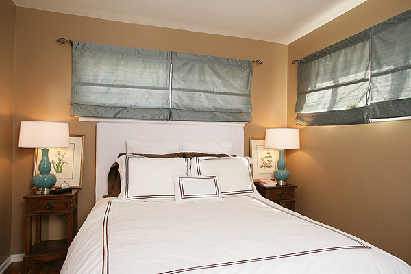 Simple bedroom with white linens with embroidered trim, tan walls and Tiffany blue lmaps