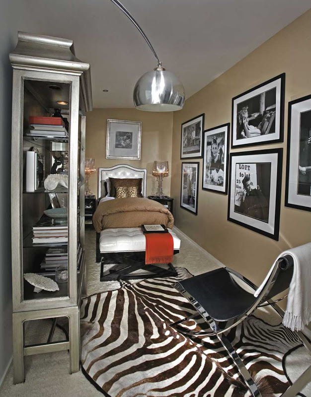 Bedroom with a zebra print rug, silver bookshelf, leather headboard and large black and white framed prints of Hollywood stars