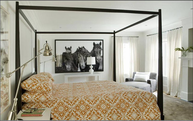 Bedroom with dark wood four poster canopy bed with orange and white printed duvet cover and a black and white print of horses