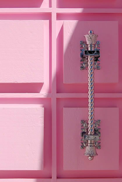 Close up of elegant silver door knob on a pink raised panel front door