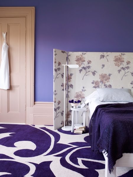 Upholstered room screen doubles as a floral headboard in a purple bedroom