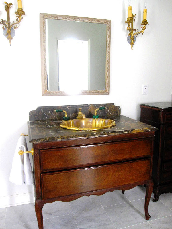 Antique two drawer wood dresser re purposed into a bathroom vanity with burnished gold sink and Port Laurent marble counter top in a master bathroom