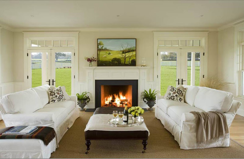 Symmetrical white living room with dueling sofas, a fireplace with a wood mantel and tow glass French doors