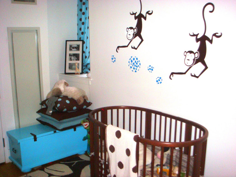 Nursery with dark brown walnut stained wood Stokke Sleepi Crib from tottini, a turquoise trunk, blue and brown polka dot curtains and two monkey decals on the wall