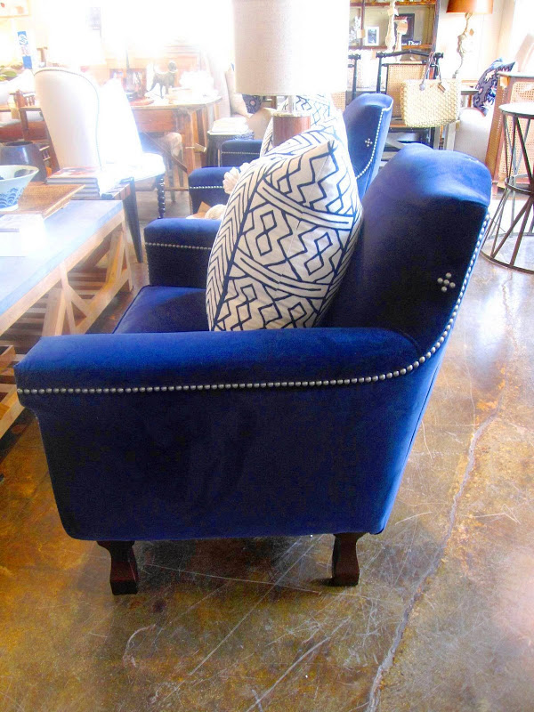 Side view of a dark blue velvet armchair with wood legs and pewter nailhead trim from Mecox Gardens