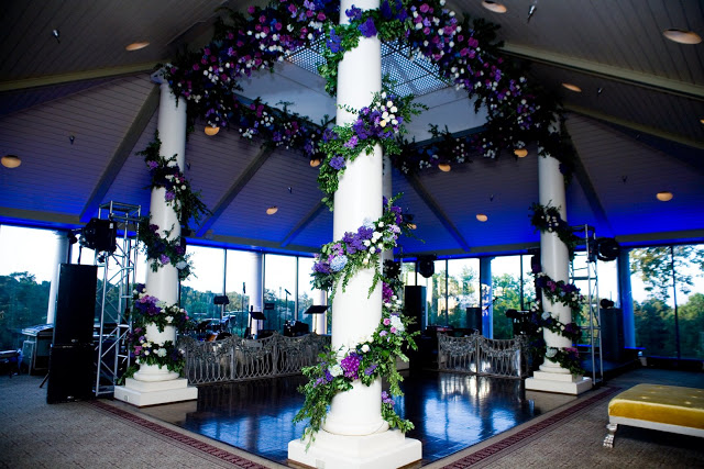 Wedding reception dance floor flanked by white classic columns wrapped in floral garlands by Delaney Todd Bagwell