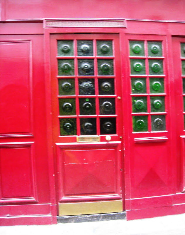 High gloss red wood door in Paris with thick green glass panes that look like the bottom of a bottle