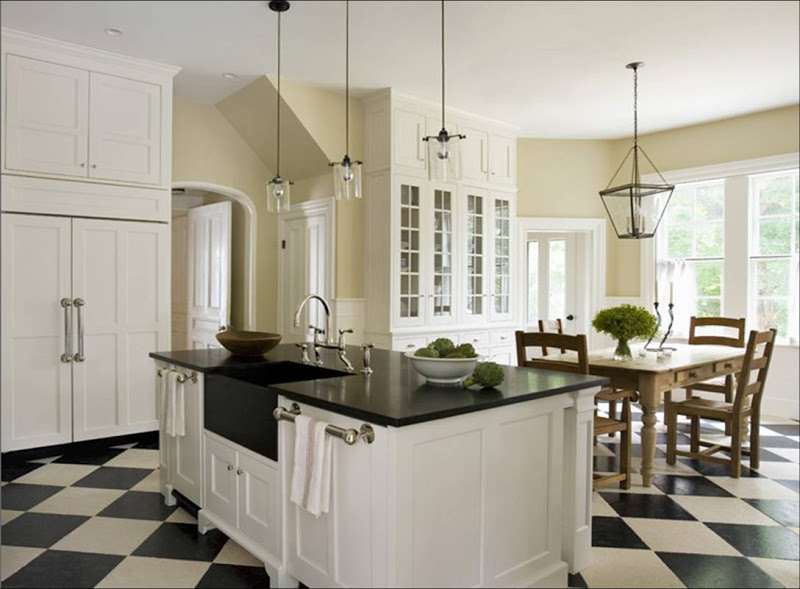 Kitchen with black and white checkerboard tile floor, glass upper cabinets, a wood farmhouse style table and metal lanterns