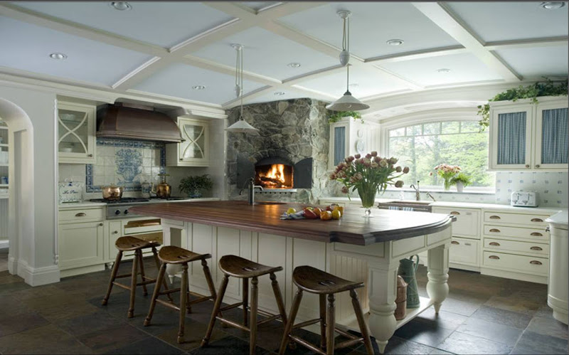 Rustic kitchen with a stone covered pizza oven, wood island counter top, bright white cabinets and drawer pulls, stone tile floor and arched coffered ceiling