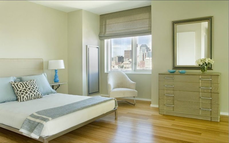 Serene bedroom with grey chest of drawers, upholstered headboard, roman shades and a Kelly Wearstler Imperial Trellis accent pillow