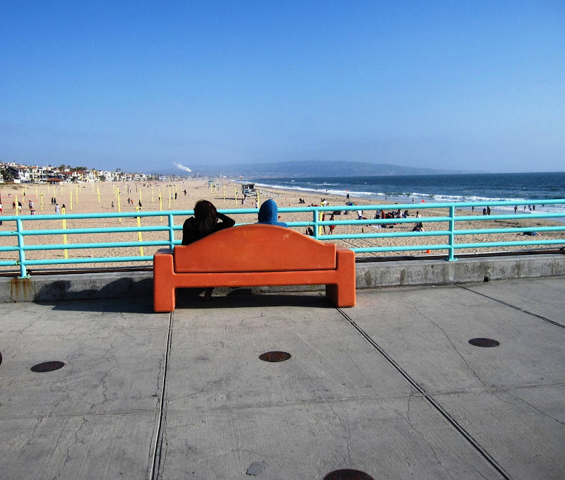 Orange bench on the pier at Manhattan Beach overlooking the water and sand