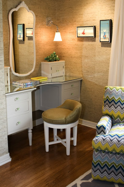 Guest bedroom in a Hancock Park home after remodeling with seagrass wallpaper, a bright chevron printed armchair and a white desk with a glass top