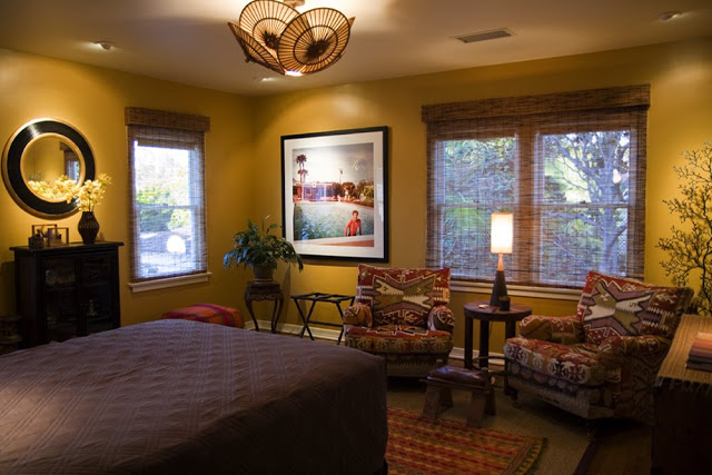 Guest bedroom in a Hancock Park home after remodeling with yellow walls, armchairs upholstered in an ethnic print and treasures from the couples travels