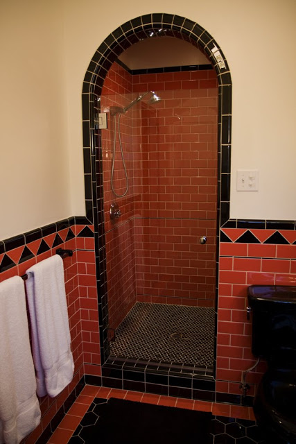 Guest bathroom in a Hancock Park home after remodeling with arched shower, coral subway tile walls and black hexagon tile floor