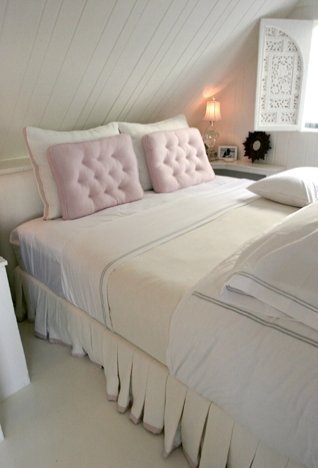 Beach house bedroom with twin bed with pink tufted accent pillows 